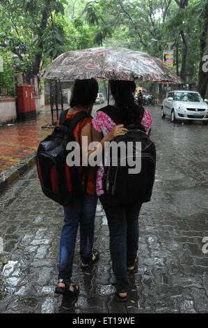 Girls holding d'un parasol marche sur rue pavée, dans la pluie monsieur# 364 Banque D'Images