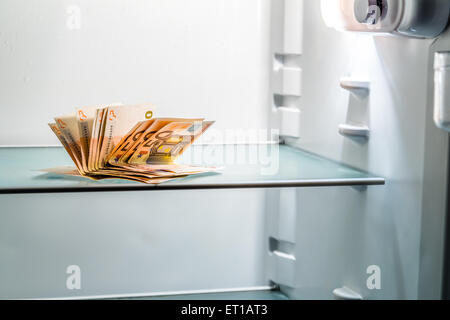 De l'argent frais dans le réfrigérateur : une poignée de billets de 50 euros éclairé par la lumière froide d'un réfrigérateur vide Banque D'Images