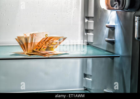 De l'argent frais dans le réfrigérateur : une poignée de billets de 50 euros éclairé par la lumière froide d'un réfrigérateur vide Banque D'Images