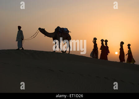 Les hommes et femme avec camel grimper dune de sable d'khuhri ; ; ; Inde Rajasthan Jaisalmer Banque D'Images