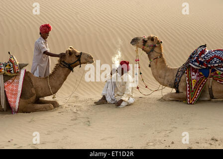 Les hommes avec des chameaux qui reste dans le désert de Rajasthan Jaisalmer ; khuhri ; Inde ; Banque D'Images