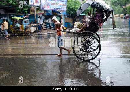 L'homme tirant part Rickshaw avec passager sur street Kolkata West Bengale Inde Asie Banque D'Images