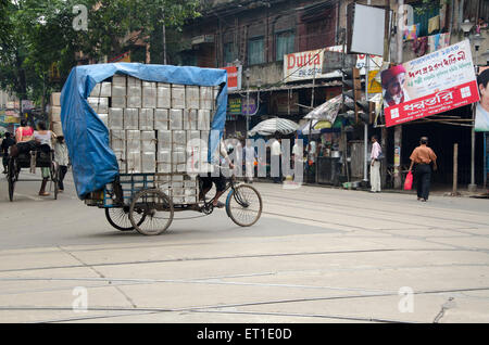 Homme portant des bidons d'étain sur cycle rickshaw Kolkata West Bengale Inde Asie Banque D'Images