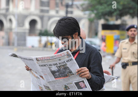 Personne lisant le journal Taj Mahal hotel après une attaque terroriste par deccan mujahedeen le 26 novembre 2008 à Bombay Mumbai Inde - 154530 soa Banque D'Images