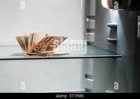 De l'argent frais dans le réfrigérateur : une poignée de billets de 50 euros éclairé par la lumière froide d'un réfrigérateur vide Banque D'Images