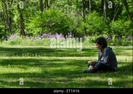 Femme assise en vertu de l'arbre dans le paysage du parc, United States. Banque D'Images