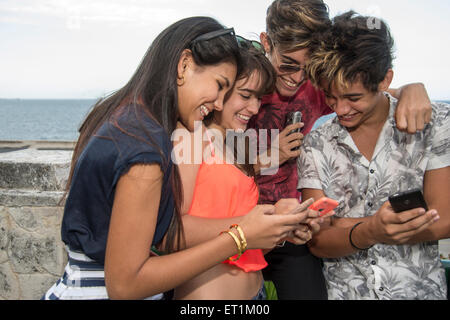 Groupe de jeunes s'amusant avec les téléphones mobiles Banque D'Images