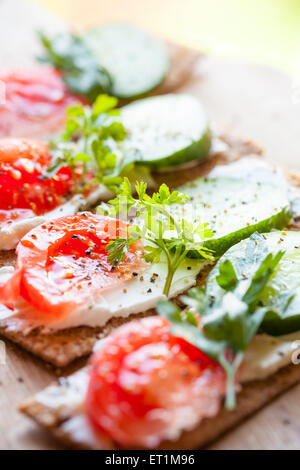 Alimentation saine. Des sandwichs de pain croustillant seigle finlandais, fromage à pâte molle, le concombre, la tomate, le persil et le poivre noir Banque D'Images