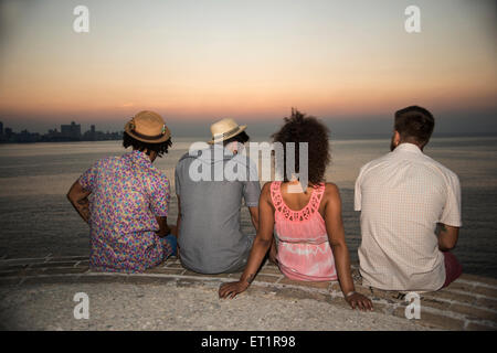 Quatre amis regardant un coucher du soleil Banque D'Images