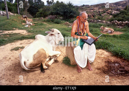 Sanskrit érudit avec ordinateur portable et vache, Melkote, Melukote, Thirunarayanapuram, Pandavapura taluk, district de Mandya, Karnataka, Inde, Asie Banque D'Images