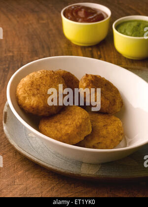 Galettes de pommes de terre frite aloo tikki dans un bol et le ketchup et chutney vert Banque D'Images