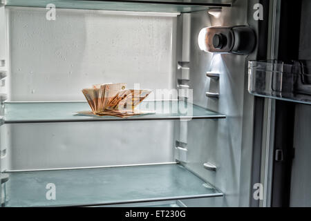 De l'argent frais dans le réfrigérateur : une poignée de billets de 50 euros éclairé par la lumière froide d'un réfrigérateur vide Banque D'Images