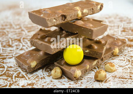 Le chocolat noir sur une table saupoudrée de cacao décorée avec des noisettes Banque D'Images