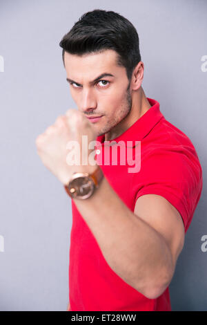 Young casual man showing fist sur fond gris et looking at camera Banque D'Images