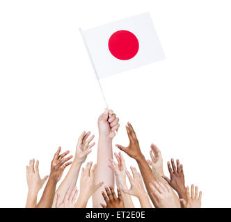 Groupe de personnes multi-ethnique pour atteindre et tenant le drapeau du Japon. Banque D'Images