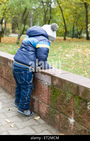 Garçon en veste et cap fun promenades dans autumn park Banque D'Images