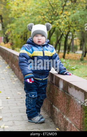 Garçon en veste et cap fun promenades dans autumn park Banque D'Images