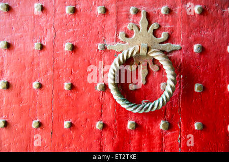 Ancien heurtoir sur la porte peinte en rouge à la cathédrale de Winchester UK Banque D'Images