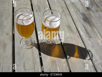 Deux bières sur la table en bois rustique à l'extérieur dans le soleil. Banque D'Images