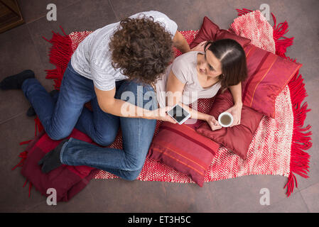 Mid adult man en utilisant un téléphone mobile et sa femme de boire du café à côté de lui, Munich, Bavière, Allemagne Banque D'Images