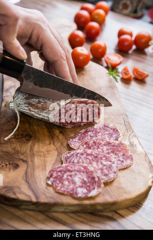 La main de personne chopping saucisse avec couteau, Allemagne Banque D'Images