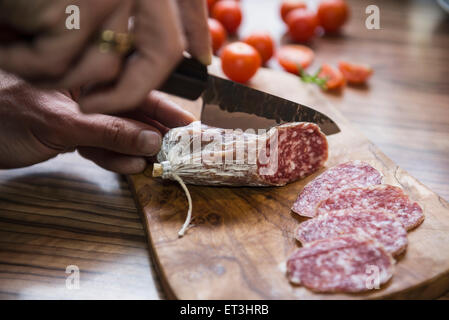 La main de personne chopping saucisse avec couteau, Allemagne Banque D'Images