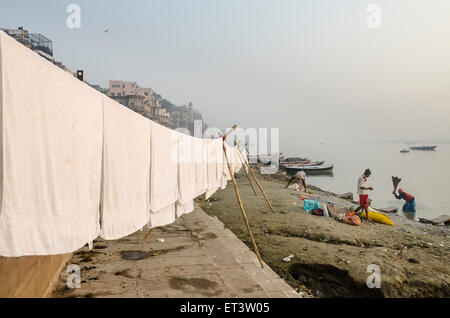 Les gens se lavent le linge de lit sur les bords du Gange à Varanasi Banque D'Images