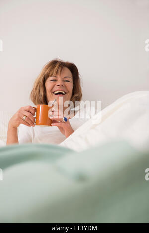 Hauts femme à sa chambre, boire du thé le matin, Munich, Bavière, Allemagne Banque D'Images