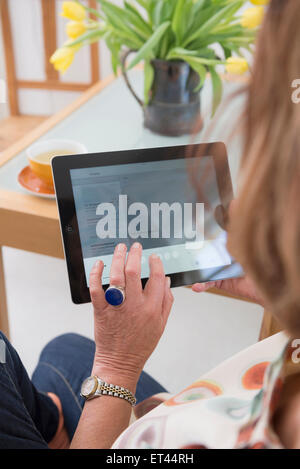 Vue arrière du senior woman sitting et à l'aide d'une tablette numérique, Munich, Bavière, Allemagne Banque D'Images