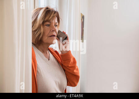 Senior Woman talking on a mobile phone à choqué, Munich, Bavière, Allemagne Banque D'Images