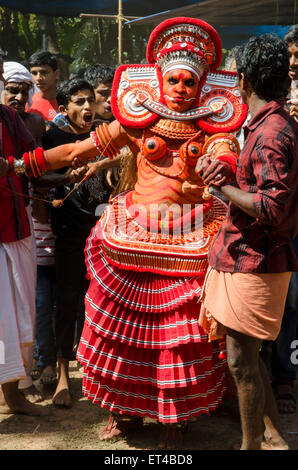 Un danseur est poussé et tiré dans le cadre de l'ancienne tradition des Thayyam de Malabar dans le nord du Kerrala Banque D'Images