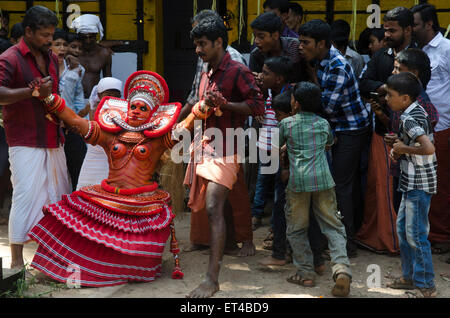 Un danseur en transe profonde est tiré autour de l'arène au cours de l'ancienne tradition des Thayyam de Malabar dans le nord du Kerrala Banque D'Images