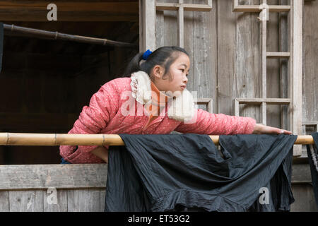 Jeune fille Miao Accueil Travailler avec un chiffon en coton traditionnel tissé, Basha Village des armes à feu, la province du Guizhou, Chine Banque D'Images