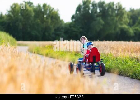 Deux enfants heureux, riant garçon et son drôle de petite soeur, adorable bébé fille, jouer ensemble profiter de rendez-vous panier voiture Banque D'Images