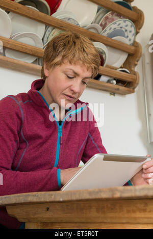 Mature Woman using digital table en cuisine, Bavière, Allemagne