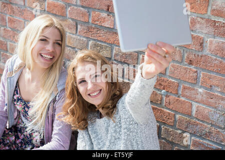 Deux amis en tenant avec sa tablette numérique selfies, Munich, Bavière, Allemagne Banque D'Images