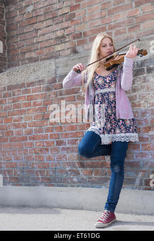 Portrait of teenage girl playing violin en face du mur de briques, Munich, Bavière, Allemagne Banque D'Images