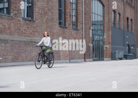 Young woman sitting in front of brick wall, Munich, Bavière, Allemagne Banque D'Images