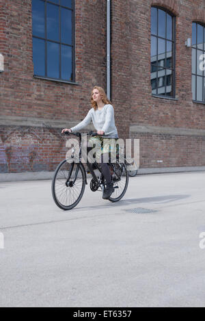 Young woman sitting in front of brick wall, Munich, Bavière, Allemagne Banque D'Images