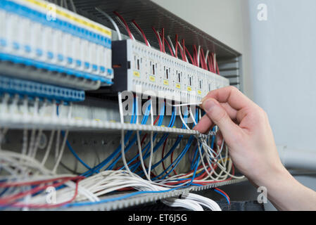 Close-up of electrician installing distribution par câble dans la boîte à fusibles, Munich, Bavière, Allemagne Banque D'Images