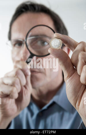 Homme d'affaires examinant une pièce d'euro avec une loupe, Bavière, Allemagne Banque D'Images