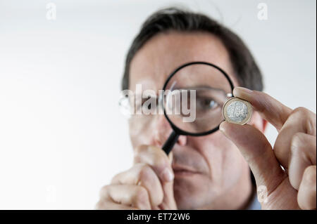 Homme d'affaires examinant une pièce d'euro avec une loupe, Bavière, Allemagne Banque D'Images