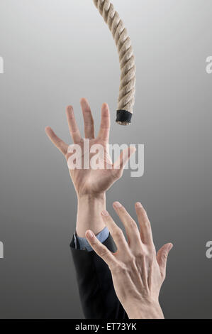 Mains d'homme d'affaires atteignant une corde pour le salut, Bavière, Allemagne Banque D'Images