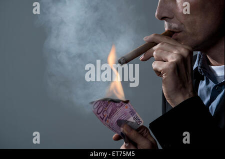 Homme d'affaires allumant un cigare avec des billets de banque, Bavière, Allemagne Banque D'Images