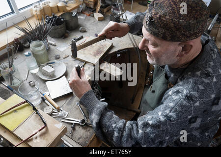 Senior male goldsmith frapper poinçons en atelier, Bavière, Allemagne Banque D'Images