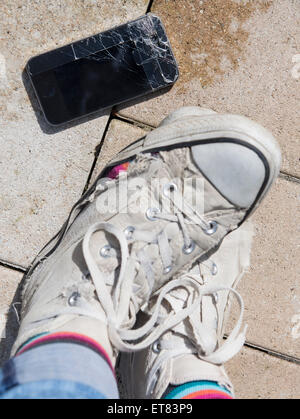 La jambe de personne avec des chaussures de toile déchirée et craquelée Allemagne Bavière smartphone Banque D'Images