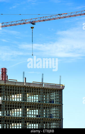 Grue de construction sur chantier contre le ciel bleu. Banque D'Images