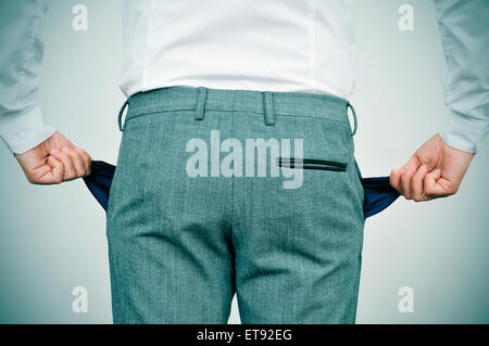 Businessman wearing a white shirt et pantalon gris montre ses poches vides, vu de derrière Banque D'Images