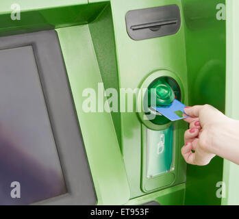 Femme insère une carte en plastique dans l'ATM Banque D'Images