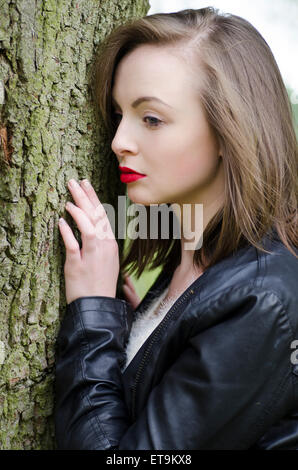 Young woman standing by l'arbre Banque D'Images